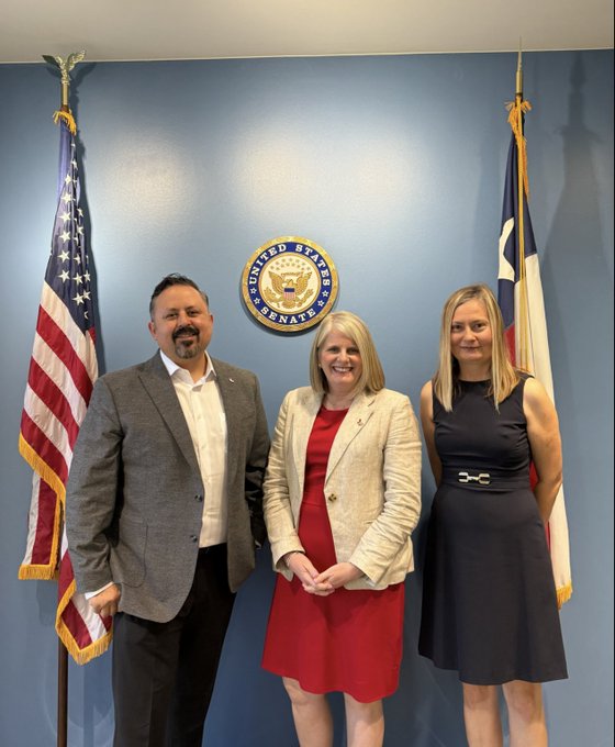 Three people posing in front of the United States Senate seal with American and Texas flags in the background.