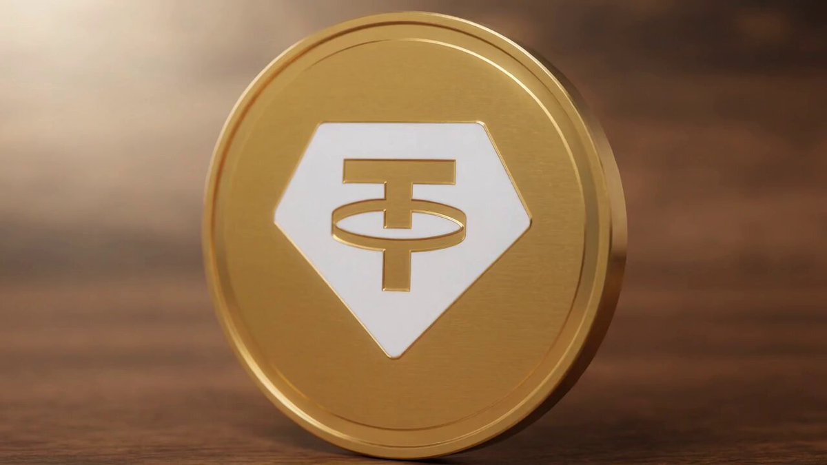 The image features a golden coin with a white "T" logo, which appears to be a T-Coin or Bitcoin token. The coin is placed on a wooden surface against a brown background. There are no texts or other objects present in the image.
