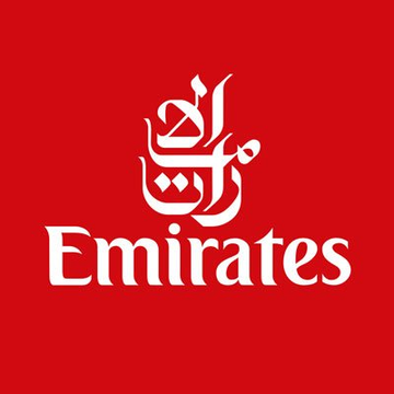 The image displays the Emirates logo, featuring white Arabic calligraphy above the "Emirates" wordmark set against a bold red background. This branding aligns with the news of Emirates officially integrating crypto payments for flight bookings, representing the airline embracing digital currency for transactions.