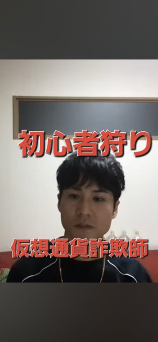 The image features a man with black hair wearing a black shirt, sitting against a white wall. The background of the photo includes Chinese characters that read "1カ月以上 YouTube更新放置しても誰もコメントもしないのは、どういうことなんでしょうね". This text appears to be in a foreign language, possibly Chinese.

The man is sitting on the left side of the image and looking at the camera with an expression of surprise or shock. The background behind him has a red color that contrasts with his black shirt.