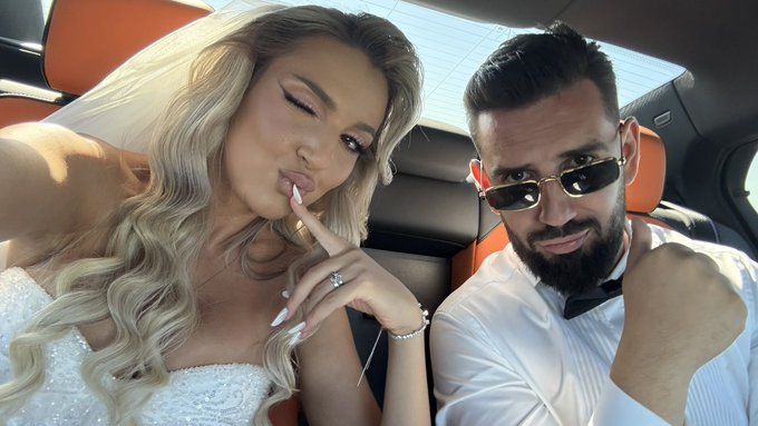 A bride and groom take a selfie inside a car, with the bride in a white dress playfully pouting and the groom wearing sunglasses and a bow tie, capturing a candid moment that reflects the caption's theme of lifelong commitment—suggesting this marriage is their ultimate "HODL for life."