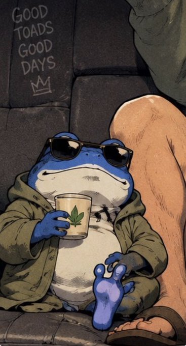A cartoon illustration of a blue toad wearing sunglasses and a green jacket, relaxing on a couch while holding a mug with a cannabis leaf on it; graffiti reading "GOOD TOADS GOOD DAYS" with a crown is visible on the wall behind.