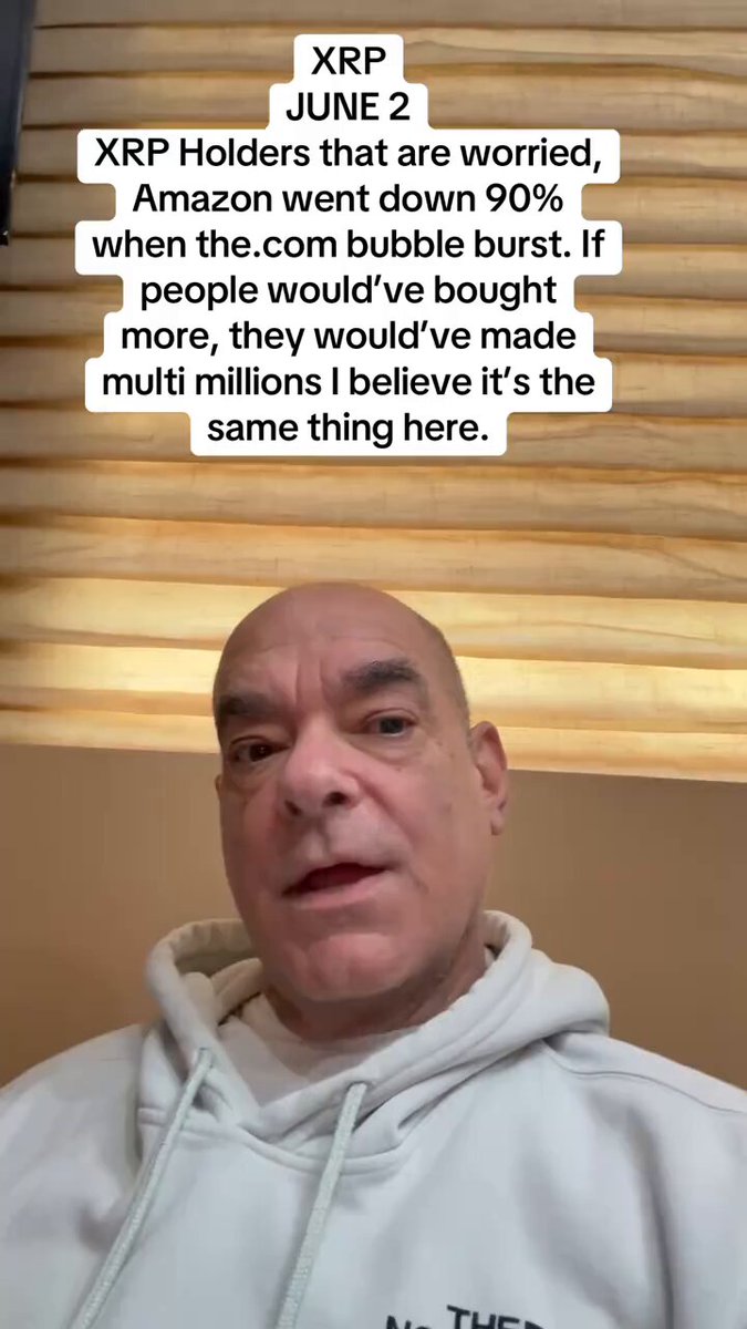 The image features a man wearing a white hoodie, sitting against a brown wall and looking directly at the camera. His expression appears serious as he seems to be engaging with the viewer or responding to their questions. The caption of the image reads "XRP JUNE2 XRP Holders don' t be worried, Amazon dropped 90% because of macro reasons, XRP is only going down on macro fears and bitcoin". 

The man's response to these questions appears to be an explanation or comment about the current state of XRP, possibly suggesting that it might not be as valuable as it once was or discussing the potential reasons behind its drop in value. The image seems to have a negative tone due to the somber expression on the man's face and his response to the questions posed by viewers.
