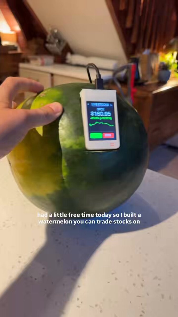 The image features a person holding a cut-in-half watermelon, with a small electronic device attached to one of its halves. The device appears to be a smartphone or tablet connected to an app that tracks the weight of the watermelon. The text in the image reads "i used a watermelon to buy $SPCX".