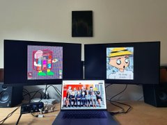 A dual-monitor computer setup with various anime and group images displayed on the screens.