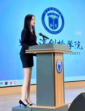 An Asian woman in a black blazer and skirt stands at a podium speaking at what appears to be Zhejiang International Studies University (浙江外国语学院).