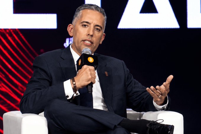A man in a dark suit speaks into a microphone with a "bt" logo while gesturing during what appears to be a conference panel discussion. The image relates to the post about Strive's $109M Bitcoin purchase, likely featuring the company's leadership discussing their significant BTC accumulation strategy.