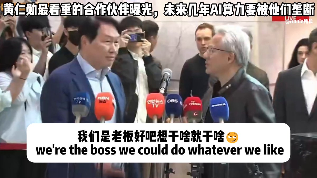 The image shows two men standing at microphones during an event or press conference. One man has his hand raised while the other one appears to be speaking into a microphone, possibly addressing the audience. The background of the image features multiple people gathered around them, indicating that this is likely a significant occasion with many attendees.