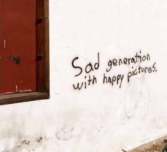 Graffiti on a white wall reading 'Sad generation with happy pictures.'