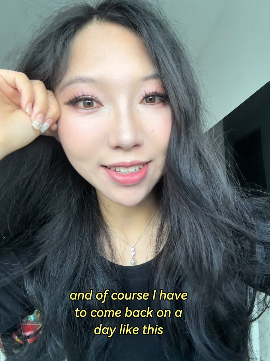 A woman with long dark hair, pink eyeshadow, and a delicate necklace takes a selfie with the caption "and of course I have to come back on a day like this." The image accompanies a post about her application to become a UGC creator for @Poly_Perps, likely introducing herself as a candidate for the role.