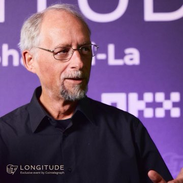 An older man with glasses and a gray goatee speaks at an event with a purple backdrop displaying partial text including "h-La" and "THX." The watermark reads "LONGITUDE Exclusive event by Cointelegraph," connecting to the post featuring Adam Back's quote about Bitcoin being self-sovereign rather than democratic.