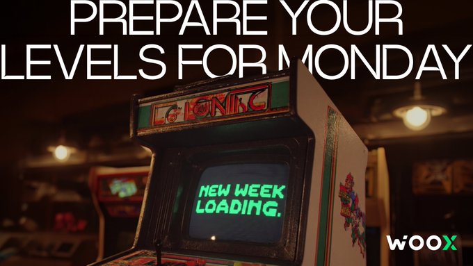 The image features a retro arcade game with neon green lights and a large screen displaying "New Week Loading". The game appears to be a classic pinball machine, reminiscent of the 80s and 90s era. The background shows a store or warehouse setting with various items on display.