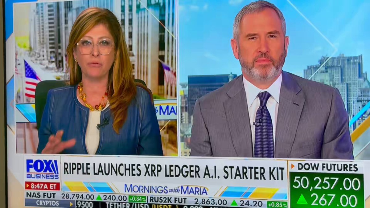 The image shows a news segment with two people, one man and one woman, standing behind a TV screen displaying the news. They are talking about Ripple Ledger technology, which has been recently launched by Ripple Ledger founder @MariaBartiromo on @FoxBusiness. The conversation seems to be focused on the potential impact of this new technology in the financial industry.