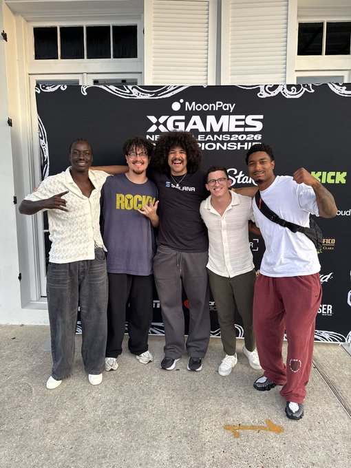 Five young men pose together smiling in front of a black backdrop banner for the 'XGAMES' event sponsored by 'MoonPay' and 'New Orleans 2026'.