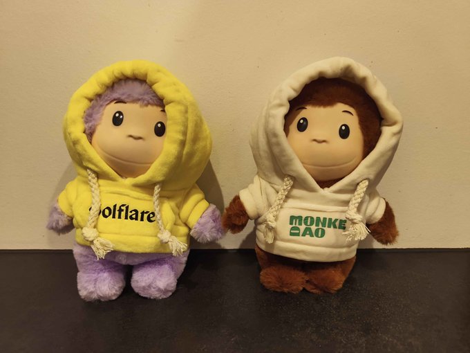 Two plush monkeys wearing hoodies with the text "Wolfcare" and "MONKE DAO" are shown, which are likely the items received from @MonkeDAO and @NomuStores.