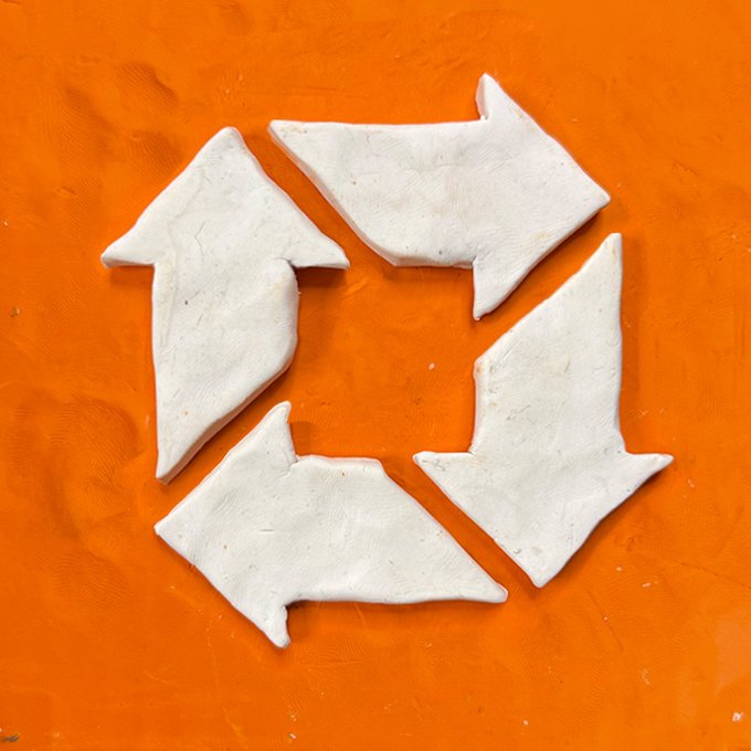 Four pieces of white clay or dough arranged in a circular pattern on an orange surface, forming a broken ring shape.
