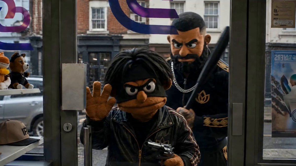 The image features a cartoon character dressed as a criminal holding a gun and standing next to another cartoon character who appears to be innocent or uninterested, possibly a store owner. The scene takes place inside a store window with various items displayed around them. The caption of the image reads "SOLANA’S MOST WANTED The Solana Ecosystem Call returns Thursday at  2pm UTC, live on @solana". This suggests that the image is related to a popular cartoon series or movie called "The Solana" and might be discussing the release date or other relevant information.