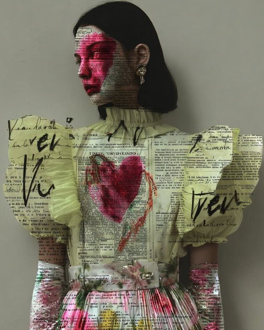 An art piece displays a woman in profile with red paint on her face and a heart painted on her chest, created using collaged text from vintage book pages.