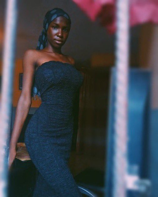 A young woman wearing a strapless dark textured dress and patterned headwrap poses confidently through a window frame in a dimly lit interior. The image doesn't visually relate to the post's text about early Bitcoin investment, but its vintage-style aesthetic may evoke a sense of nostalgia or an "early adopter" moment being referenced metaphorically.