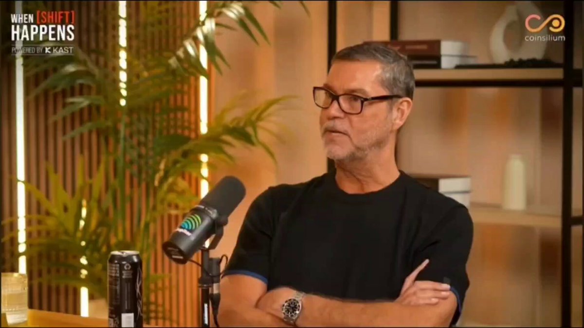 In the image, there's a man wearing glasses standing next to a microphone, possibly giving an interview or speaking at a podcast event. The background features a bookshelf filled with various items such as books and vases. The caption of the image reads "The CEO of @RealVision says Hyperliquid is a niche product with no competitive advantage." This statement suggests that the man in the image might be discussing the niche nature of Hyper Liquid, which could be related to the products displayed on the bookshelf or their potential applications in various fields.
