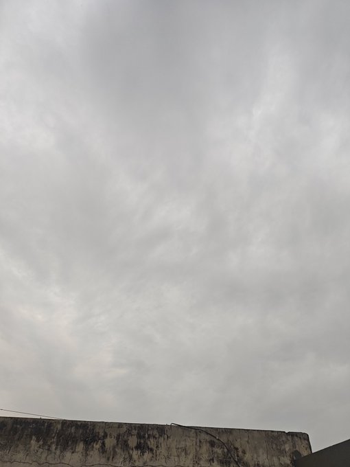 An overcast gray sky with textured clouds above the edge of a weathered concrete rooftop.