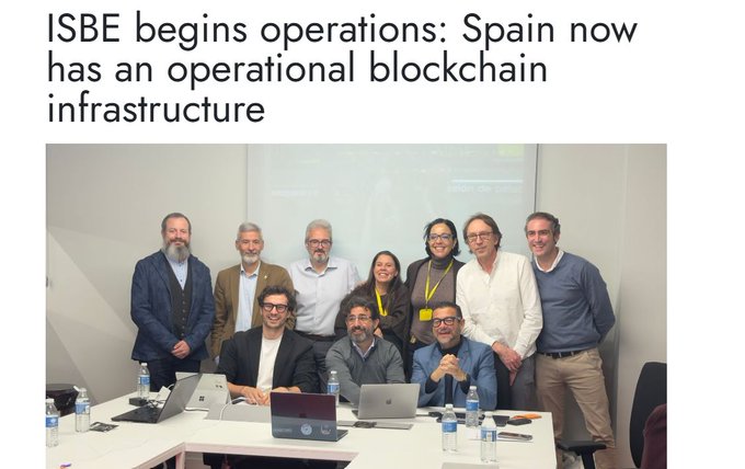 An article screenshot titled 'ISBE begins operations: Spain now has an operational blockchain infrastructure' showing a group photo of people at a conference table with laptops.