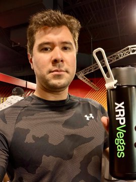 xtrp vegas logo on a black water bottle, held by a man with a gray t-shirt and brown hair.