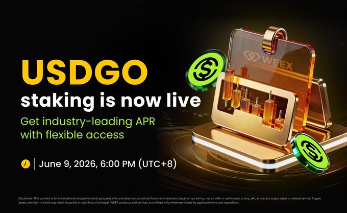 The image features a gold-colored laptop with a sticker that says "USDCGO" on it, along with some text about staking. The laptop appears to be turned off or not currently active. There are two green circles on the laptop screen, which could possibly represent coins or tokens in a cryptocurrency exchange.