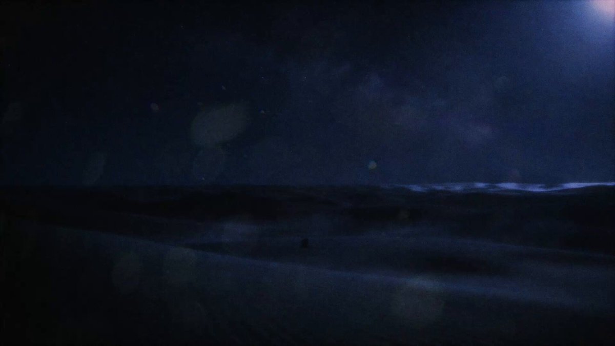 The image shows a desert landscape at night with a full moon visible in the sky, casting light over the scene. The dark blue sky contrasts with the sandy terrain below. In the foreground of the photo, there are two people standing on top of a sand dune under the moonlight. The post also mentions that "$DEUS is now listed on @Solana via Sunrise." This suggests that someone has posted this image on social media platforms like Instagram or Twitter to share their experience and location with friends and followers.