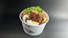A cup of Mazesoba (brothless ramen) topped with green onions, ground meat, and a halved soft-boiled egg.