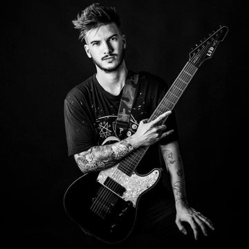 A black-and-white portrait of a tattooed young man holding an electric guitar, his arms adorned with visible ink. The image ties into the post's theme of transitioning from physical guitar collecting in his 20s to collecting JPEGs (likely NFTs) in his 30s, while still playing and pursuing a new passion.