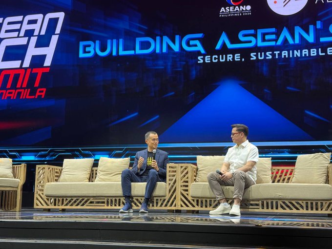 Two men sit on a wicker couch on stage at 'ASEAN TECH SUMMIT MANILA', with a backdrop reading 'BUILDING ASEAN'S SECURE, SUSTAINABLE'.