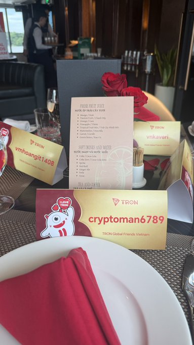 A table setting at a TRON Global Friends Vietnam event featuring name placards for 'cryptoman6789', 'vnhoangit1408', and 'vnkaveri' with TRON branding and a restaurant menu.