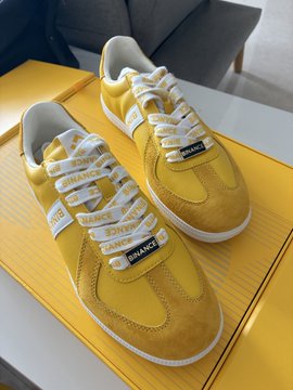 A pair of yellow suede sneakers with white laces and 'CHANGE' branded labels rests on a yellow box.