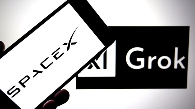 A hand holds a smartphone displaying the SpaceX logo in front of a larger screen showing the Grok AI logo. The image visually illustrates the partnership between SpaceX and Grok, highlighting Grok's new availability as a free Google Workspace add-on.
