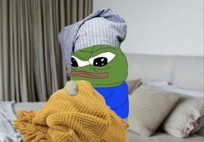 A Pepe the Frog meme character wearing a striped nightcap and wrapped in a yellow blanket, looking sad in a bedroom setting.