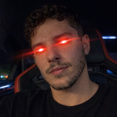 A young man with curly hair and red laser-eye effects sits in a gaming chair, looking directly at the camera in a moody, dimly lit setting. The glowing red eyes and intense stare playfully match the caption's call-to-action, suggesting he's "locking on" to viewers ready to drop their addresses.