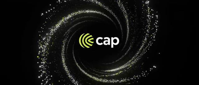 A glowing spiral of white and green particles swirls around a central logo featuring the text "cap" in white, accompanied by a bright green icon resembling sound waves or a target. The dynamic vortex design visually reinforces the announcement that the $CAP token is officially live, conveying energy and momentum for the launch.