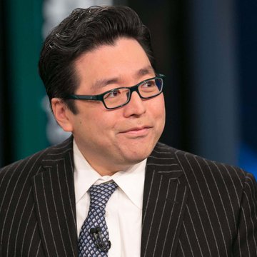 A portrait of an Asian man with glasses wearing a dark pinstripe suit, white shirt, and patterned tie, appearing to speak on a panel.