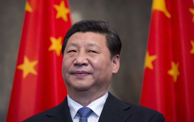 The image shows a man wearing a suit standing in front of two red flags with yellow stars, likely representing China and the United States (also known as the Trump administration). The man has his head tilted back towards the camera, giving him an assertive and confident look on his face. In the post below the photo, someone comments, "Ohh... you thought we were joking when @justinsuntron said TRON ($TRX) to $20?!?". This comment suggests that there is humor involved in the conversation or situation depicted in the image, possibly due to the reference made by another person to Trump's name.