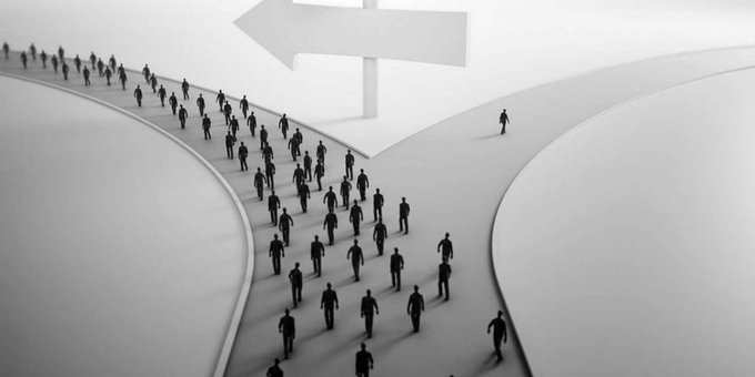 A black-and-white illustration shows a large crowd of silhouetted figures walking along a curved path toward a giant arrow sign, while a single lone figure walks away on the opposite diverging road. The image visually represents the growing community of XRP holders finding unity in numbers, paralleling the post's sentiment that holding $XRP no longer feels lonely as more investors join the movement.