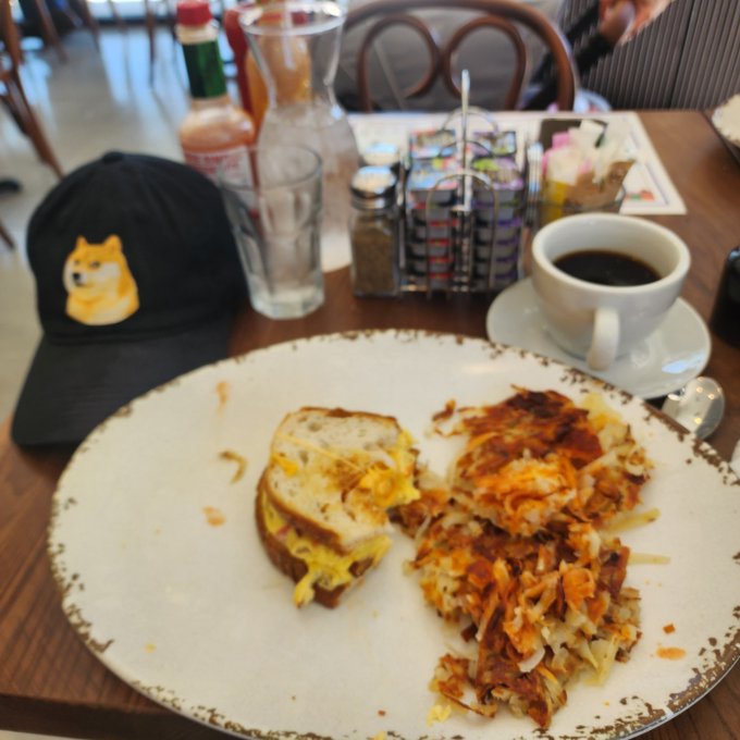 iced tea, coffee, and breakfast items are arranged on a table with a black hat featuring a dog design.