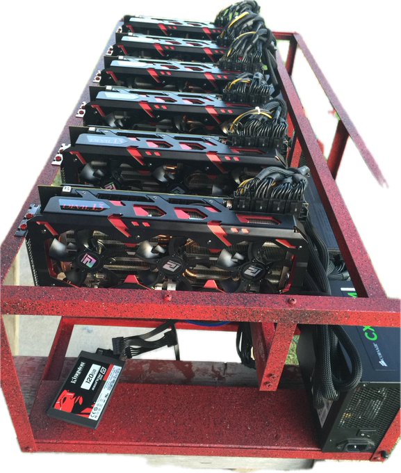 A cryptocurrency mining rig setup in a red metal frame containing multiple Sapphire branded RX series graphics cards, powered by a Gamdias power supply.