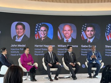 A panel discussion on stage featuring several speakers seated in front of a backdrop displaying headshots and names of US House of Representatives members: John Medel, Harriet Hageman, William Timmons, Gabe Evans, and Steve (partially visible).