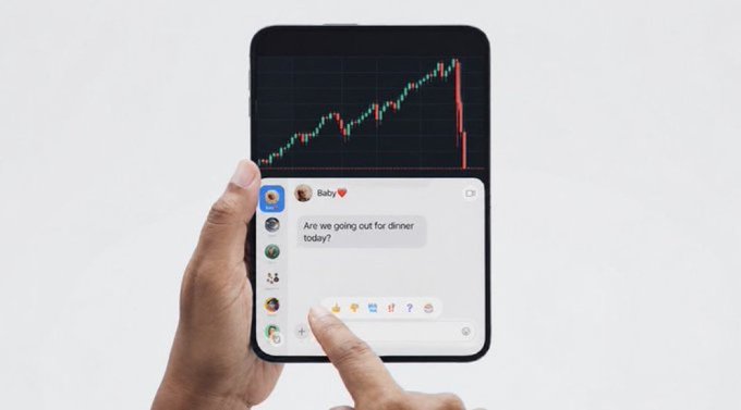 A person holds a foldable smartphone displaying a stock chart with a sharp downward trend alongside a text message from "Baby" asking "Are we going out for dinner today?" The dramatic market crash displayed above the mundane relationship query cleverly illustrates how a financial downturn—even one significant enough for crypto investors to "dump their iPads"—still can't ruin date night plans.
