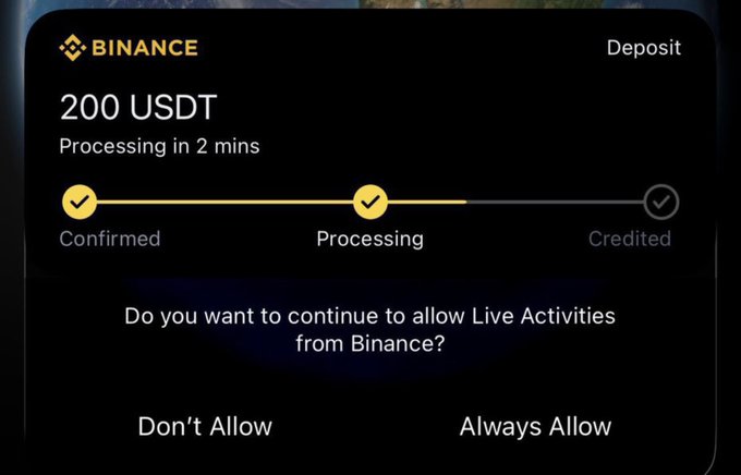 A Binance app notification shows a 200 USDT deposit currently "Processing," expected to be credited in 2 minutes, along with a system prompt asking to allow "Live Activities from Binance." The image is being used as fake "proof" in a giveaway scam, where the poster claims to be giving away $200 to two random commenters and requests wallet addresses—making this a common crypto giveaway fraud.