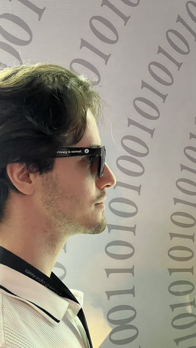 The image features a man wearing sunglasses, possibly a young man with short hair, who appears to be looking off into the distance or at something out of frame. The background consists of a white wall adorned with black numbers and symbols, which could potentially represent data or information related to privacy concerns in the digital age.

The caption "Privacy is normal." suggests that the image might be promoting awareness about privacy issues or encouraging people to protect their personal information online.