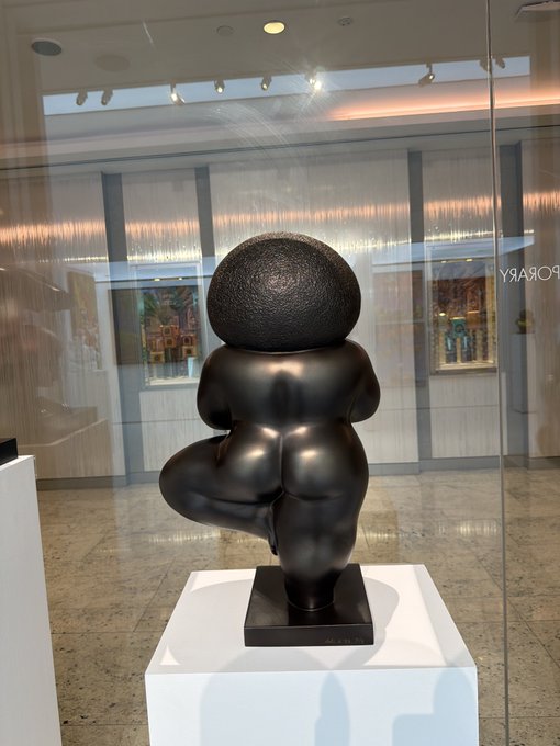 The image depicts a bronze-colored sculpture of a rounded, abstract female figure with an oversized textured head, displayed on a white pedestal inside a glass-walled gallery space, with "POSARY" partially visible in reverse on the glass.

The post indicates a temporary break from social media, and the serene, contemplative sculpture—a meditation on feminine form and stillness—visually echoes the introspective, restorative mood of stepping away from digital distractions.