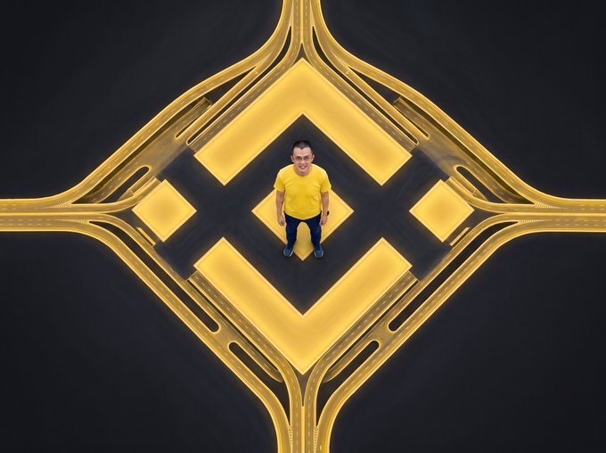An aerial top-down shot of a man in a yellow shirt standing at the center of a symmetrical golden-lit diamond and cross intersection on dark asphalt, similar to the composition in image 3.