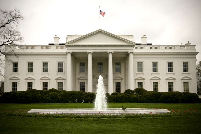 The White House, with the American flag flying atop and a fountain in the foreground, hosts a major crypto and prediction markets summit bringing together President Trump, SEC Chair Paul Atkins, CFTC Chair Michael Selig, and leaders from Coinbase, Gemini, Ripple, Polymarket, and Kalshi.
